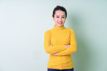 Wall Mural - Beautiful young Asian woman wearing sweater on green background