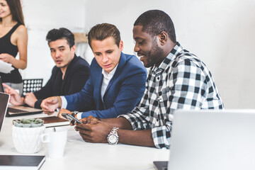 Wall Mural - A team of young office workers, businessmen with laptop working at the table, communicating together in an office. Corporate businessteam and manager in a meeting. coworking.