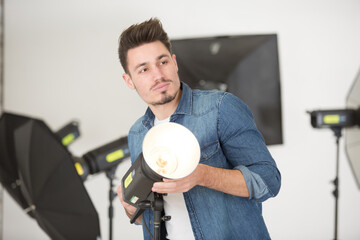 young male photographer in studio with professional lighting equipment