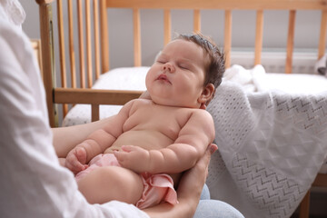 Sticker - Mother holding cute sleeping baby near crib at home