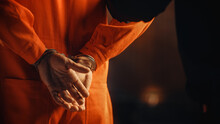 Cinematic Close Up Footage Of A Handcuffed Convict At A Law And Justice Court Trial. Handcuffs On Accused Criminal In Orange Jail Jumpsuit. Law Offender Sentenced To Serve Jail Time.