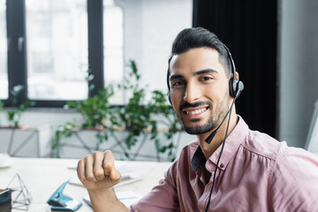 Wall Mural - Arabian businessman in headset smiling at camera in office