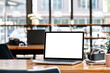 © NAMPIX - Mockup blank white screen laptop computer on wooden table in co-workspace.