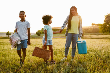 Wall Mural - Black happy family smiling while walking with bags on field