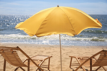 Wall Mural - Orange beach umbrella and deck chairs on sandy seashore