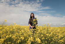 Asian Teenager Girl In Classic Blue Dress Standing In Field Of Yellow Musterd Seed Flowers
