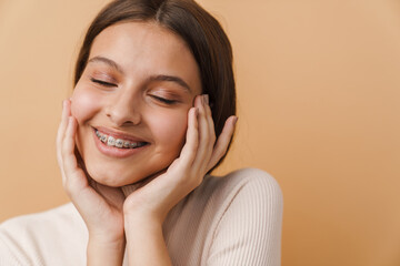 Wall Mural - Young woman touching her face and smiling at camera