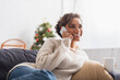 © LIGHTFIELD STUDIOS - Happy african american woman with cup talking on cellphone during christmas at home