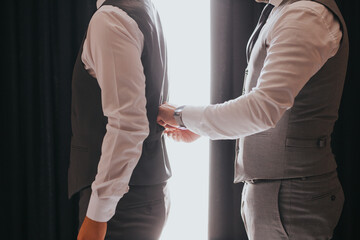 Poster - Closeup of the man helping the groom with clothes.