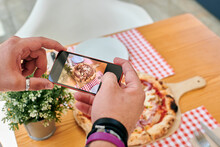Close-up Of A Man Taking Pictures Of A Pizza With His Phone
