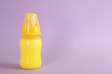 Feeding Bottle With Infant Formula On Lilac Background, Space For Text. Baby Milk