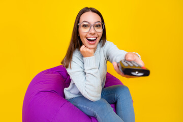 Canvas Print - Photo of cheerful amazed young woman tv switch channel remote control isolated on yellow color background