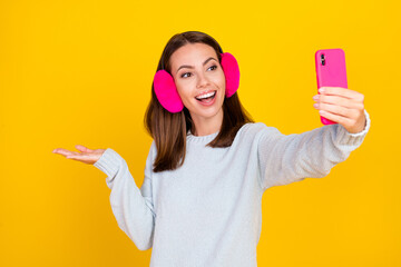 Sticker - Photo of cheerful happy woman wear earmuffs make selfie hand empty space sweater object isolated on yellow color background