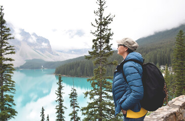 Wall Mural - Woman with backpack looking at turqouise lake and mountains