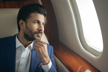 close up portrait of handsome pensive arab businessman planning project sitting on airplane looking 