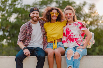 Wall Mural - happy young company of smiling friends sitting in park