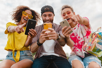 Wall Mural - happy young company of smiling friends sitting in park