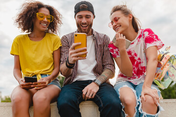 Wall Mural - happy young company of smiling friends sitting in park