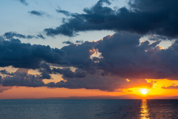 Wall Mural - Stunning dramatic, cloudy sunrise with a bright sun rising over a calm water. Natural background, Sardinia, Italy.