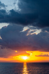 Wall Mural - Stunning dramatic, cloudy sunrise with a bright sun rising over a calm water. Natural background, Sardinia, Italy.