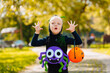 Blonde boy Portrait in spider costume with pumpkins in he hands.