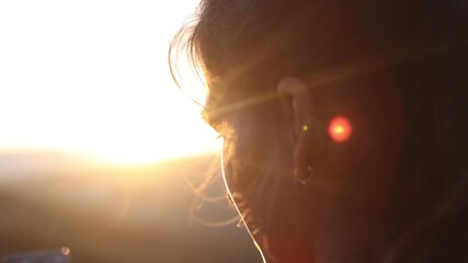 Wall Mural - girl looks at the sunset. the light of the sun shines through the girl's dark hair