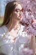 girl smelling pink flowers on a blossoming tree