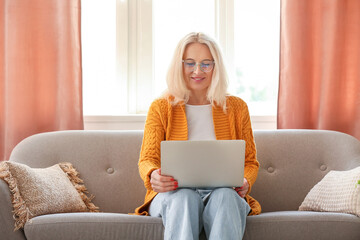 Sticker - Mature woman in eyeglasses using laptop at home