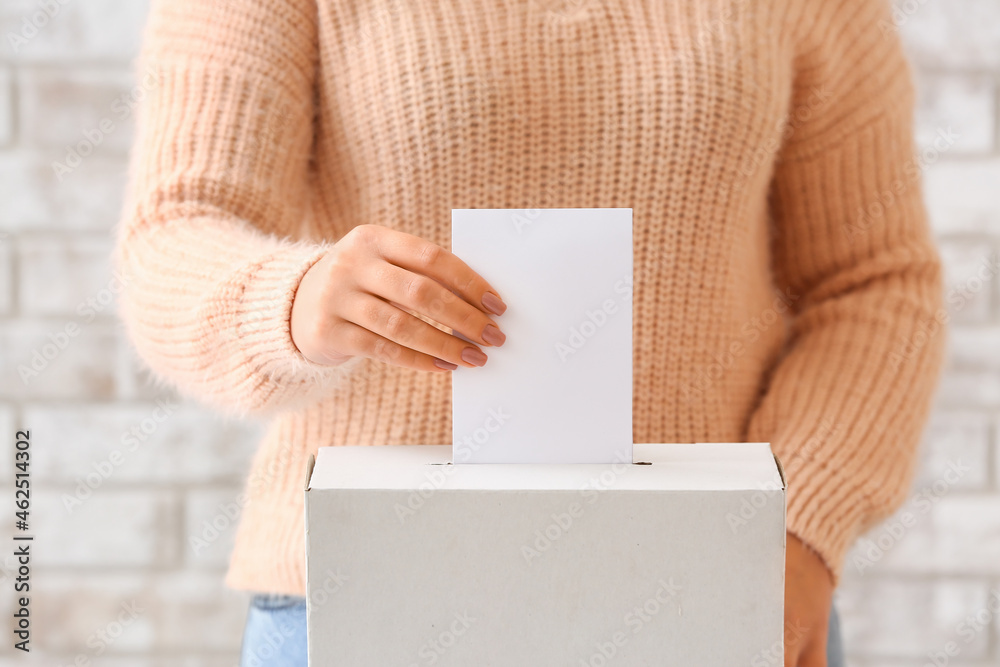 Voting woman near ballot box on light background