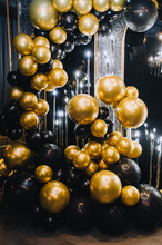 A Beautiful Photo Zone Of Round Golden And Black Balls On The Background Of The Wall.
