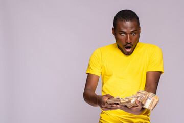 Wall Mural - young black man holding a lot of cash looks surprised and amazed