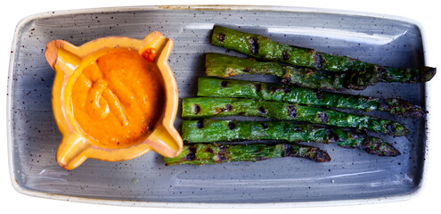 Delicious asparagus appetizer with Romesco sauce on a platter. Isolated over white background