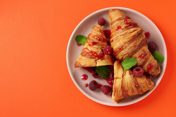 Wall Mural - Plate with croissants with raspberry jam on orange background