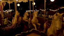 A spinning carousel with horses and elephants that rise and fall, at nightfall. High quality HD footage