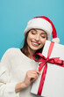 © LIGHTFIELD STUDIOS - pleased woman in santa hat holding present isolated on blue