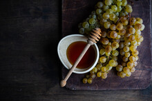 Bunch Of Grapes Next To A Bowl Of Honey And A Honey Dipper