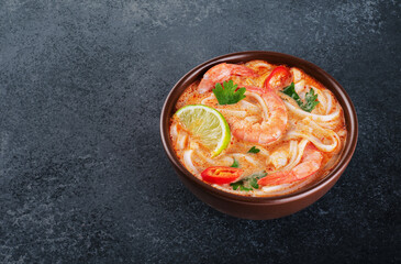 Wall Mural - Tom yum noodle soup with spices and shrimp on a dark background.