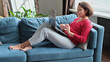 © yavdat - middle-aged woman shopping online. Woman use laptop in home. weekend in wooden armchair couch. notebook look at screen type message. computer internet
