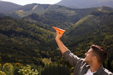 Wall Mural - Man throwing paper plane in mountains on sunny day. Space for text