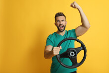 Emotional Man With Steering Wheel On Yellow Background. Space For Text