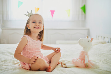 Wall Mural - Adorable little girl dressed as princess playing with unicorn