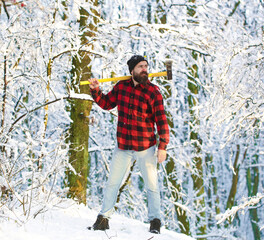 Lumberjack brutal bearded man with beard and moustache on winter day, snowy forest. Lumberjack in the woods with an ax. Bearded man in hat with a hatchet. Handsome man, hipster.