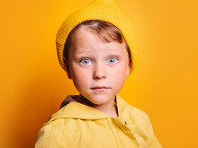 Surprised Boy Looking At Camera Against Yellow Wall In Studio
