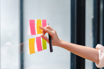 Close-up of a woman hand holding a pen affixing a note to her mirror at the office.