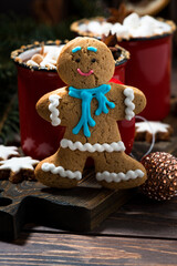 Wall Mural - gingerbread man cookies and hot chocolate on wooden background, vertical closeup