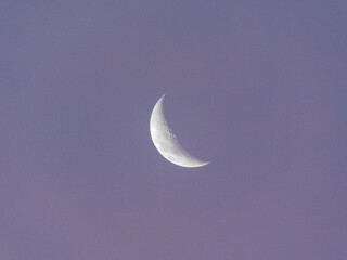 Waxing crescent moon picture with a soft purple sky in the background.