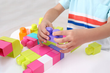 Sticker - Little child playing with colorful building blocks at table indoors, closeup