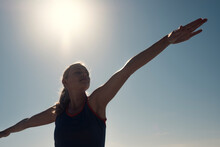 Young Woman Exercising Yoga Under Blue Sky In Backlight