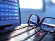 © Andrew Brookes/Westend61 - Stock market data reflecting in eyeglasses lying on laptop keyboard
