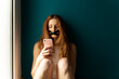 © Westend61 - Young woman with taped mouth using cell phone